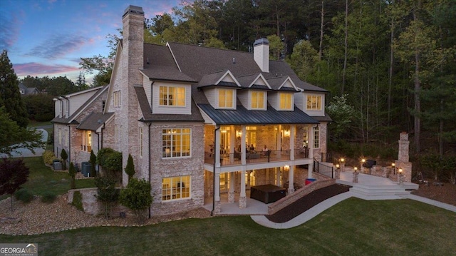 back of property featuring a chimney, a patio area, and a yard