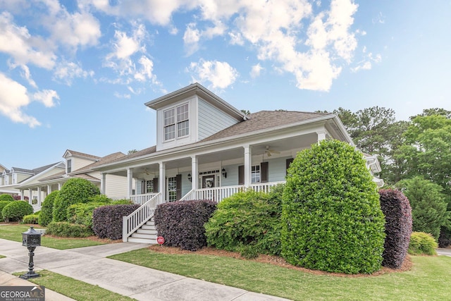 bungalow featuring a front lawn, ceiling fan, covered porch, and roof with shingles