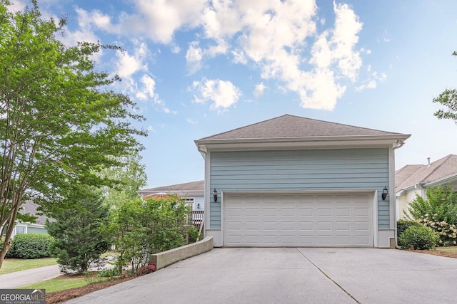 exterior space featuring a shingled roof and concrete driveway
