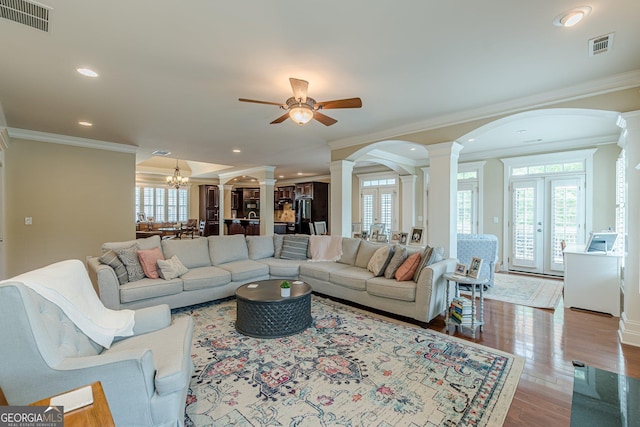 living room featuring ornate columns, visible vents, crown molding, and arched walkways