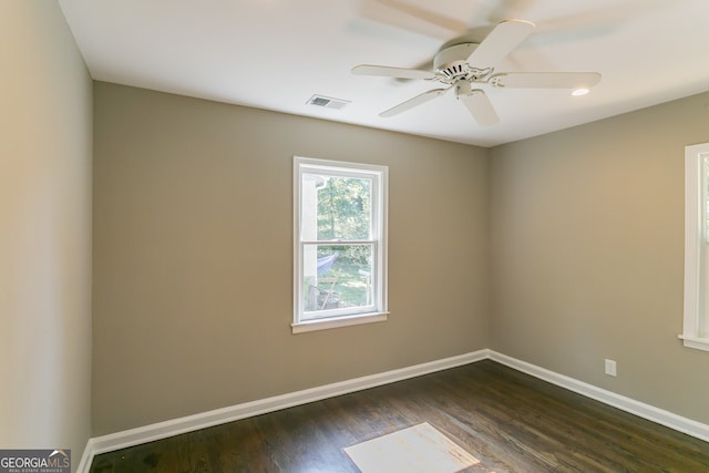 empty room featuring ceiling fan, baseboards, visible vents, and dark wood finished floors