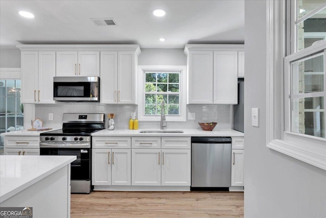 3951 Lindley Dr, Powder Springs, GA 30127 - kitchen with appliances with stainless steel finishes, a sink, white cabinets, decorative backsplash, and recessed lighting