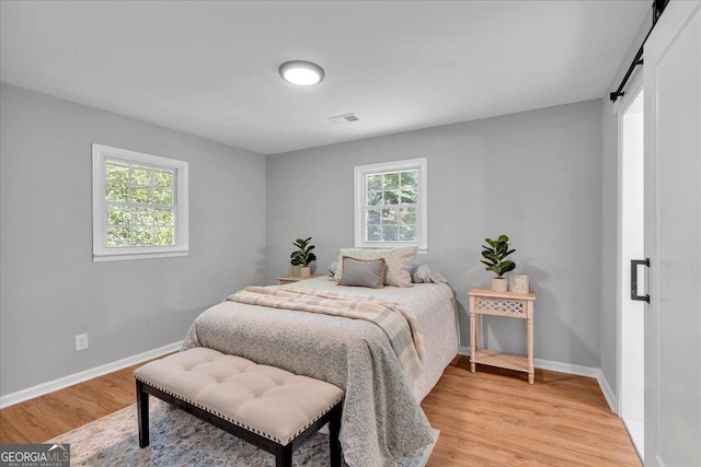 3951 Lindley Dr, Powder Springs, GA 30127 - bedroom featuring a barn door, baseboards, and light wood-style flooring