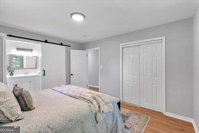 3951 Lindley Dr, Powder Springs, GA 30127 - bedroom featuring a barn door, light wood finished floors, baseboards, a closet, and a sink
