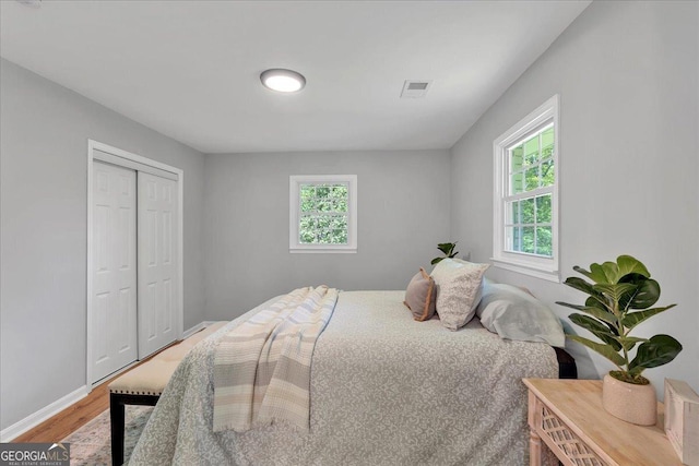3951 Lindley Dr, Powder Springs, GA 30127 - bedroom featuring multiple windows, light wood-style floors, a closet, and baseboards