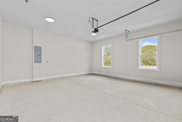garage featuring electric panel, a garage door opener, and baseboards