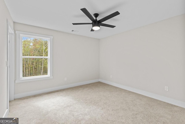 carpeted empty room with visible vents, a ceiling fan, and baseboards