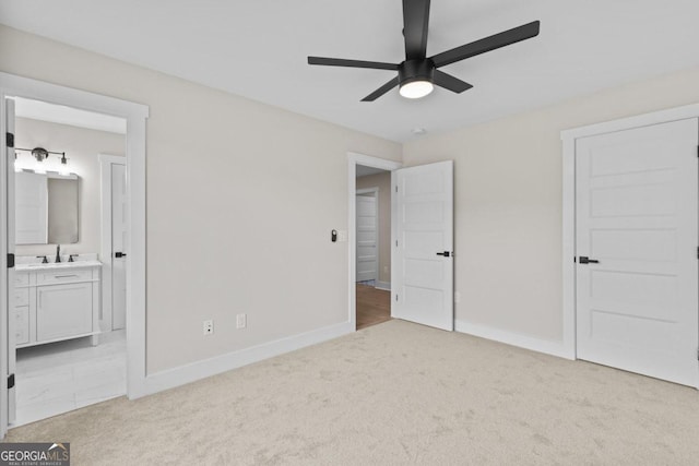 unfurnished bedroom with baseboards, ensuite bath, carpet flooring, and a sink