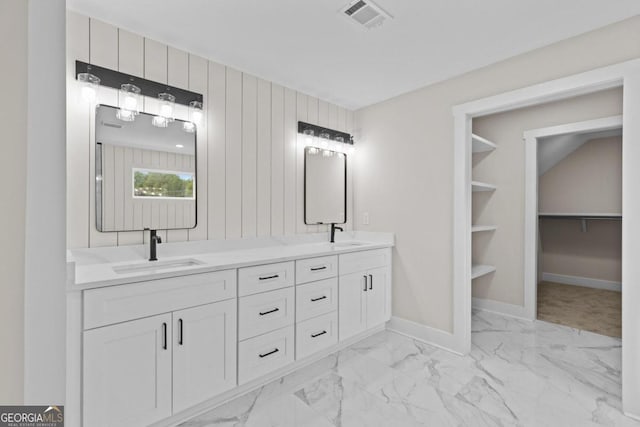 bathroom featuring a sink, marble finish floor, double vanity, visible vents, and baseboards