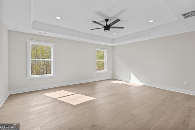 unfurnished room featuring visible vents, light wood-type flooring, and a raised ceiling