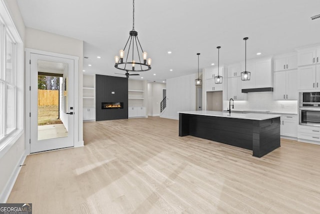 kitchen featuring a notable chandelier, light wood-type flooring, backsplash, light countertops, and white cabinets
