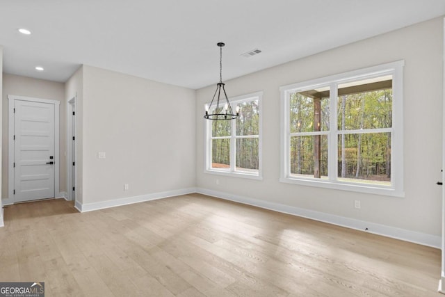 unfurnished dining area with baseboards, visible vents, a notable chandelier, and light wood-style floors
