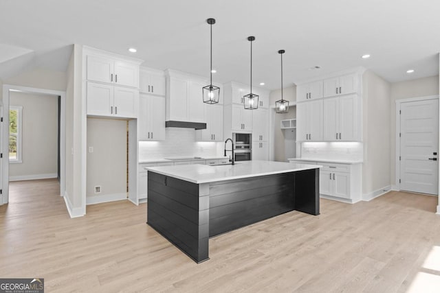 kitchen with a sink, white cabinetry, decorative backsplash, and baseboards