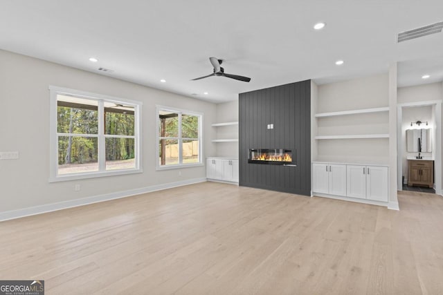 unfurnished living room featuring ceiling fan, light wood-type flooring, and baseboards