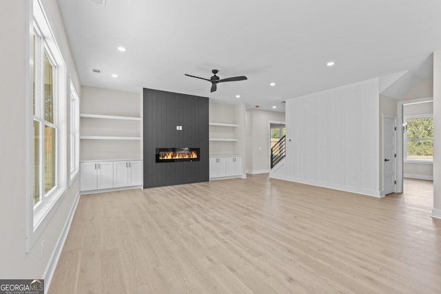 unfurnished living room with a wealth of natural light, light wood-style floors, a ceiling fan, and baseboards
