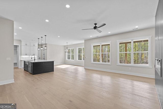 unfurnished living room featuring baseboards, ceiling fan, and light wood-style floors