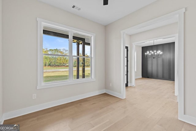 spare room featuring a wealth of natural light, visible vents, baseboards, and light wood-style floors