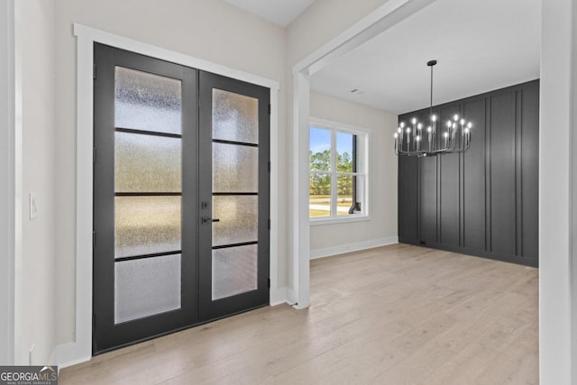 doorway featuring a chandelier, baseboards, wood finished floors, and french doors
