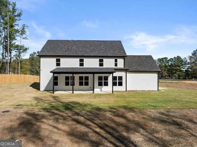 rear view of house with fence, a lawn, and a patio