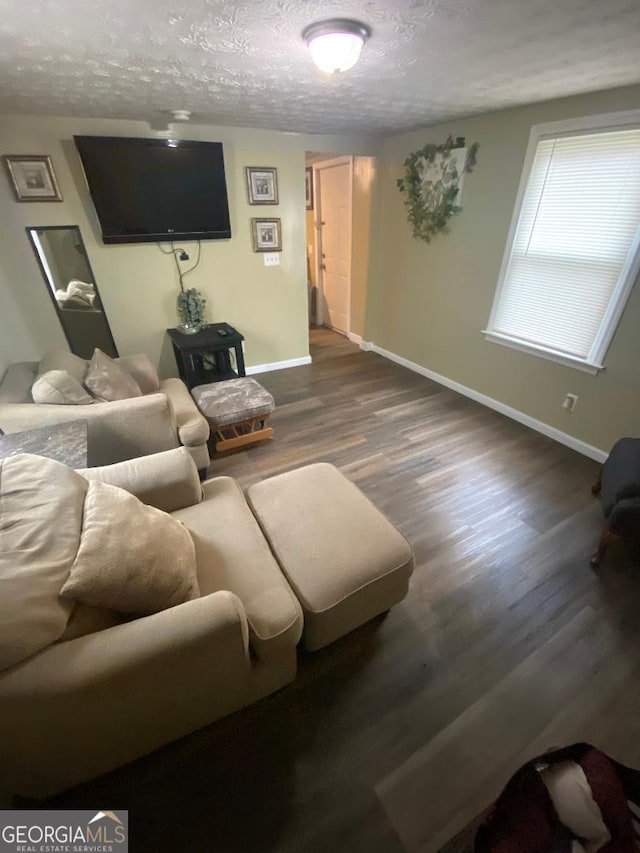 living room featuring a textured ceiling, baseboards, and wood finished floors