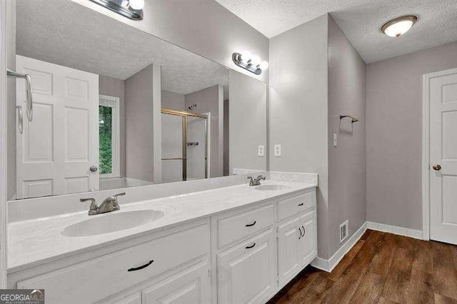 full bathroom featuring a textured ceiling, a sink, a shower stall, and visible vents