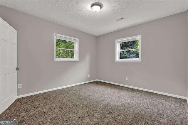 empty room featuring baseboards, visible vents, a textured ceiling, and carpet flooring