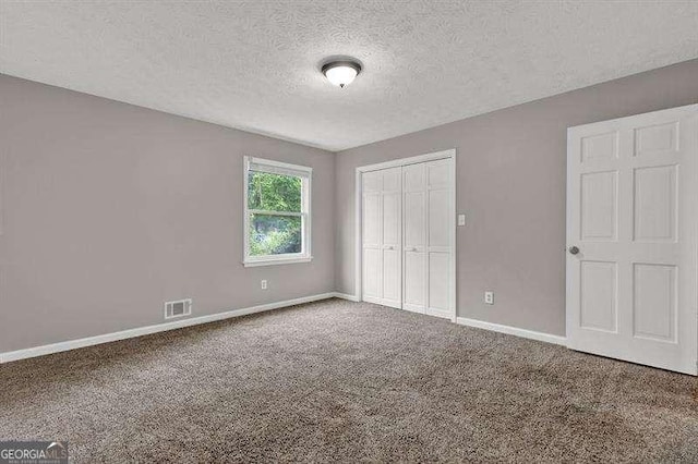 unfurnished bedroom featuring baseboards, visible vents, carpet floors, and a closet