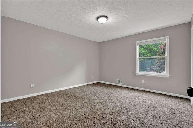 carpeted spare room featuring baseboards, visible vents, and a textured ceiling