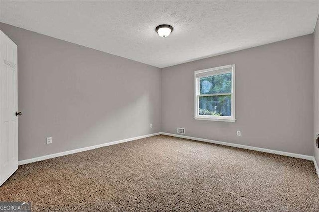 carpeted spare room featuring baseboards, visible vents, and a textured ceiling