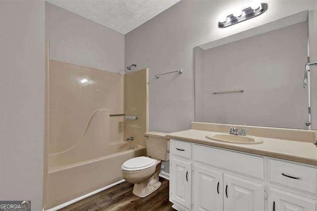 full bathroom with a textured ceiling, wood finished floors, toilet, shower / washtub combination, and vanity