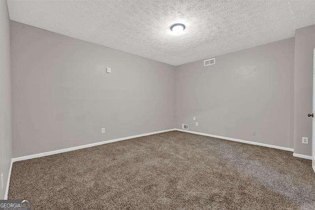 carpeted empty room with a textured ceiling, visible vents, and baseboards