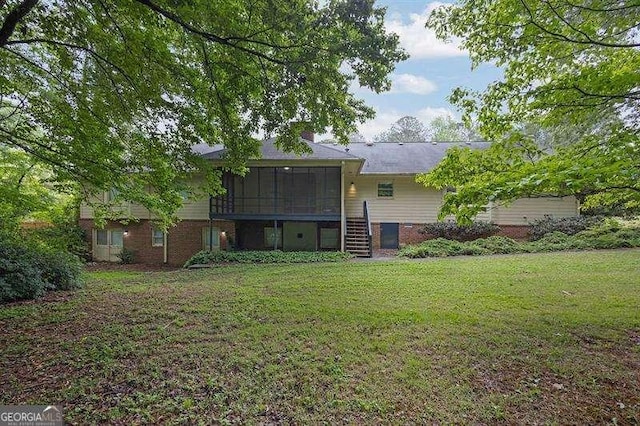 back of property featuring a lawn, stairs, brick siding, and a sunroom