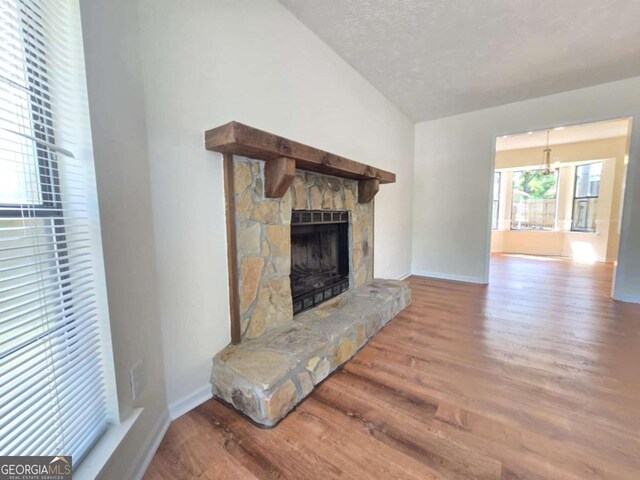 5229 Mountain Village Ct, Stone Mountain, GA 30083 - unfurnished living room featuring a textured ceiling, baseboards, vaulted ceiling, a fireplace, and wood finished floors
