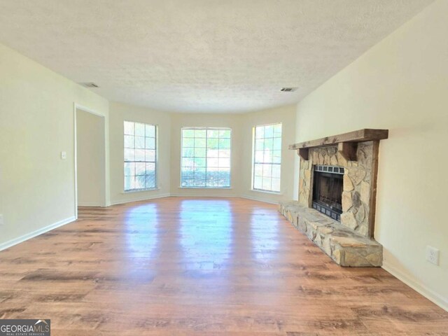 5229 Mountain Village Ct, Stone Mountain, GA 30083 - unfurnished living room with visible vents, a stone fireplace, wood finished floors, and baseboards