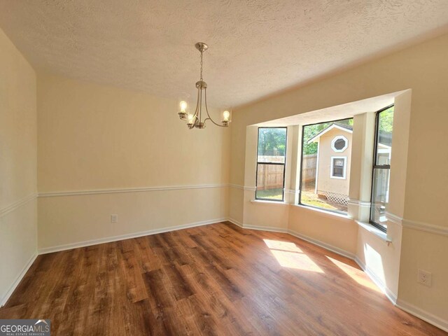5229 Mountain Village Ct, Stone Mountain, GA 30083 - unfurnished dining area with baseboards, wood finished floors, an inviting chandelier, and a textured ceiling