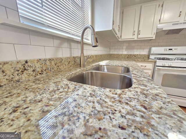 5229 Mountain Village Ct, Stone Mountain, GA 30083 - kitchen featuring tasteful backsplash, light stone countertops, under cabinet range hood, white gas range, and a sink