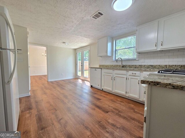 5229 Mountain Village Ct, Stone Mountain, GA 30083 - kitchen with wood finished floors, white appliances, light stone counters, decorative backsplash, and white cabinets