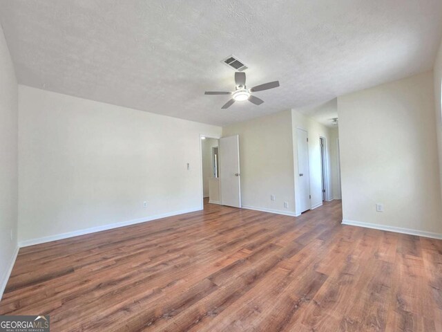5229 Mountain Village Ct, Stone Mountain, GA 30083 - empty room featuring a textured ceiling, visible vents, baseboards, wood finished floors, and a ceiling fan