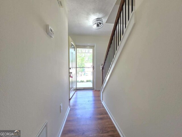 5229 Mountain Village Ct, Stone Mountain, GA 30083 - hall with wood finished floors, stairs, baseboards, visible vents, and a textured ceiling