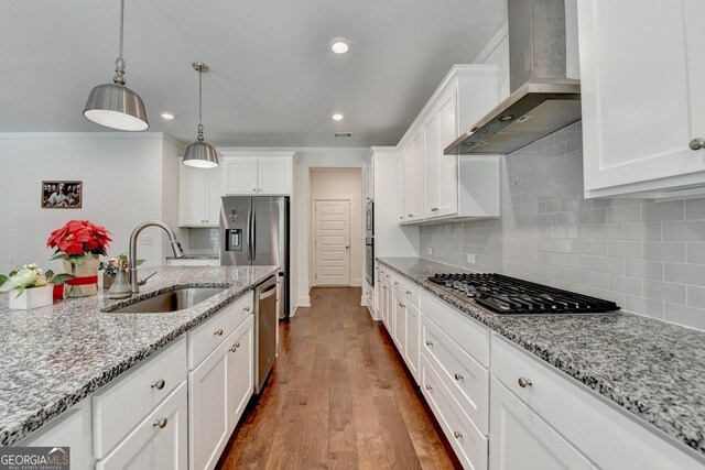 kitchen featuring white cabinets, stainless steel appliances, wall chimney range hood, and a sink