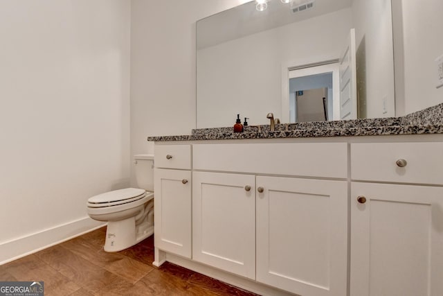 bathroom with vanity, toilet, visible vents, and baseboards