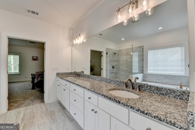 ensuite bathroom with double vanity, visible vents, a stall shower, and a sink