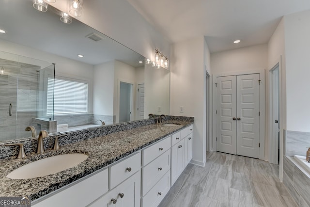 full bathroom with a stall shower, double vanity, a sink, and a bath