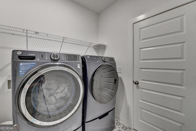 clothes washing area featuring independent washer and dryer, laundry area, and baseboards