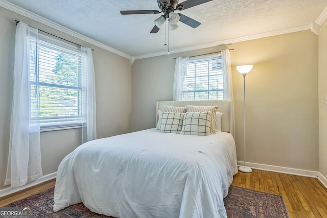 bedroom with baseboards, ornamental molding, a ceiling fan, and wood finished floors