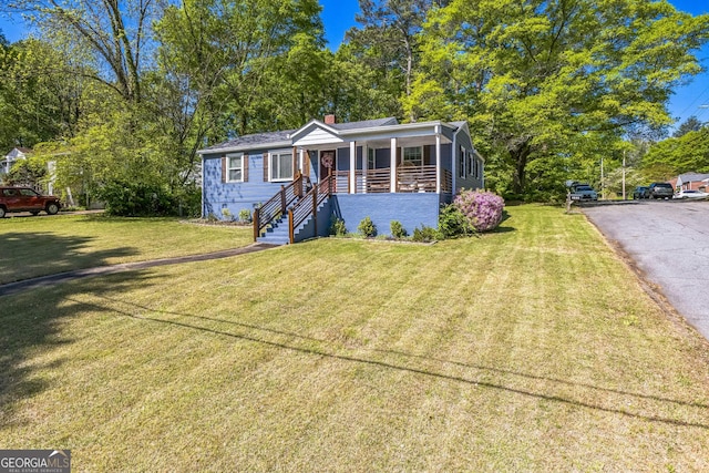 view of front of home featuring a front lawn, stairway, covered porch, driveway, and a chimney