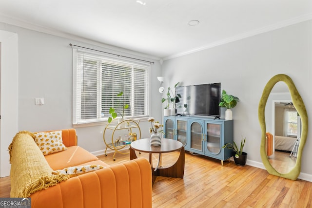 living area featuring plenty of natural light, light wood-style flooring, crown molding, and baseboards