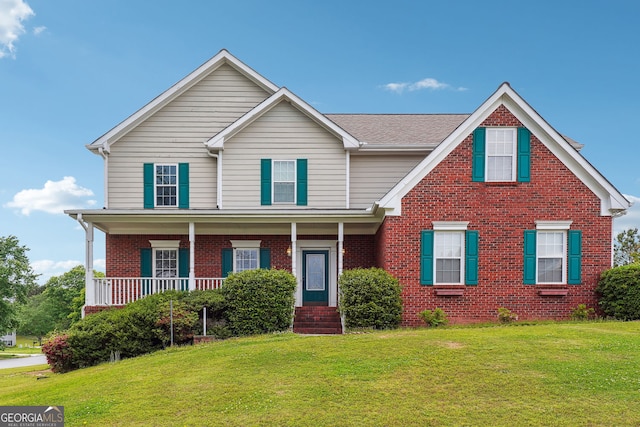 traditional home with covered porch, brick siding, and a front lawn