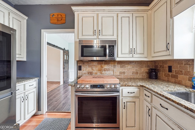 kitchen with appliances with stainless steel finishes, backsplash, and cream cabinetry