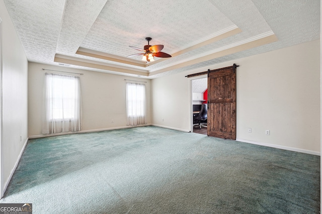 carpeted spare room with a ceiling fan, a textured ceiling, a healthy amount of sunlight, and a raised ceiling